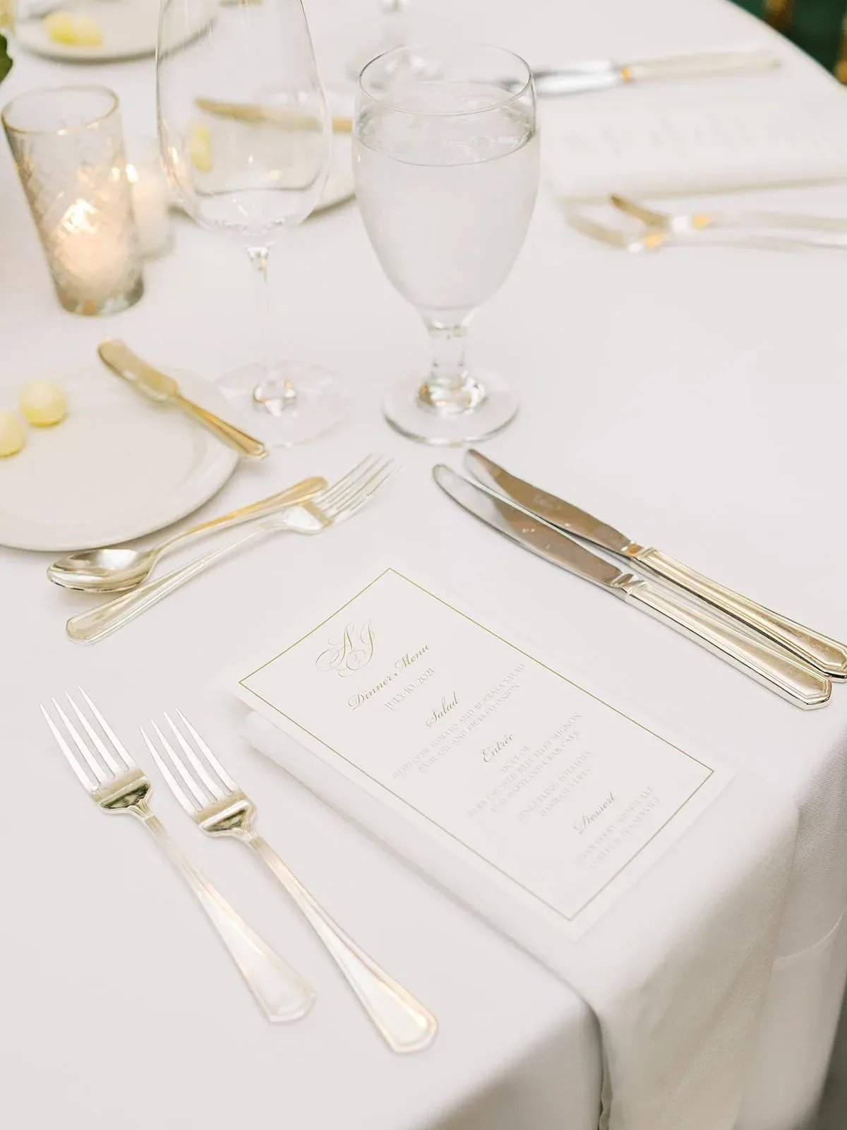 Gold-bordered dinner menu with matching monogram at a white place setting
