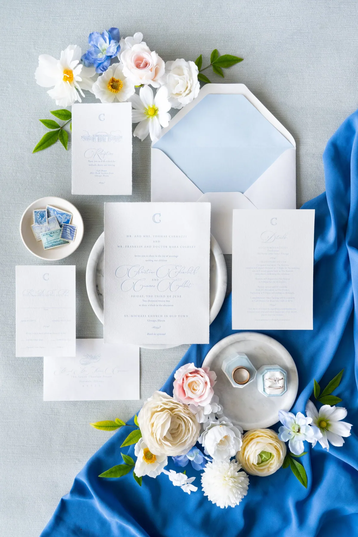 White wedding suite with a pale blue lined envelope, styled on blue fabric
