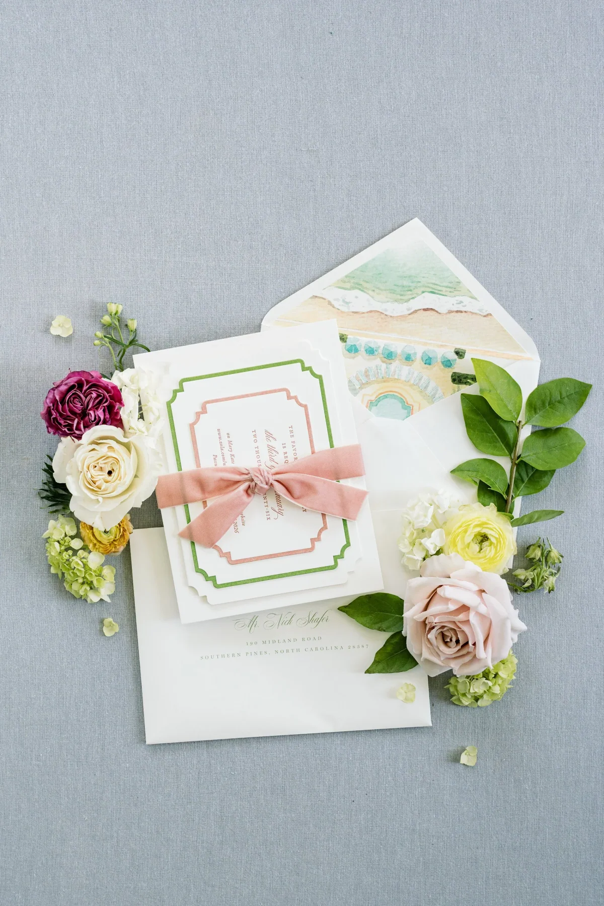 Invitation with green and blush borders, tied with a blush ribbon bow