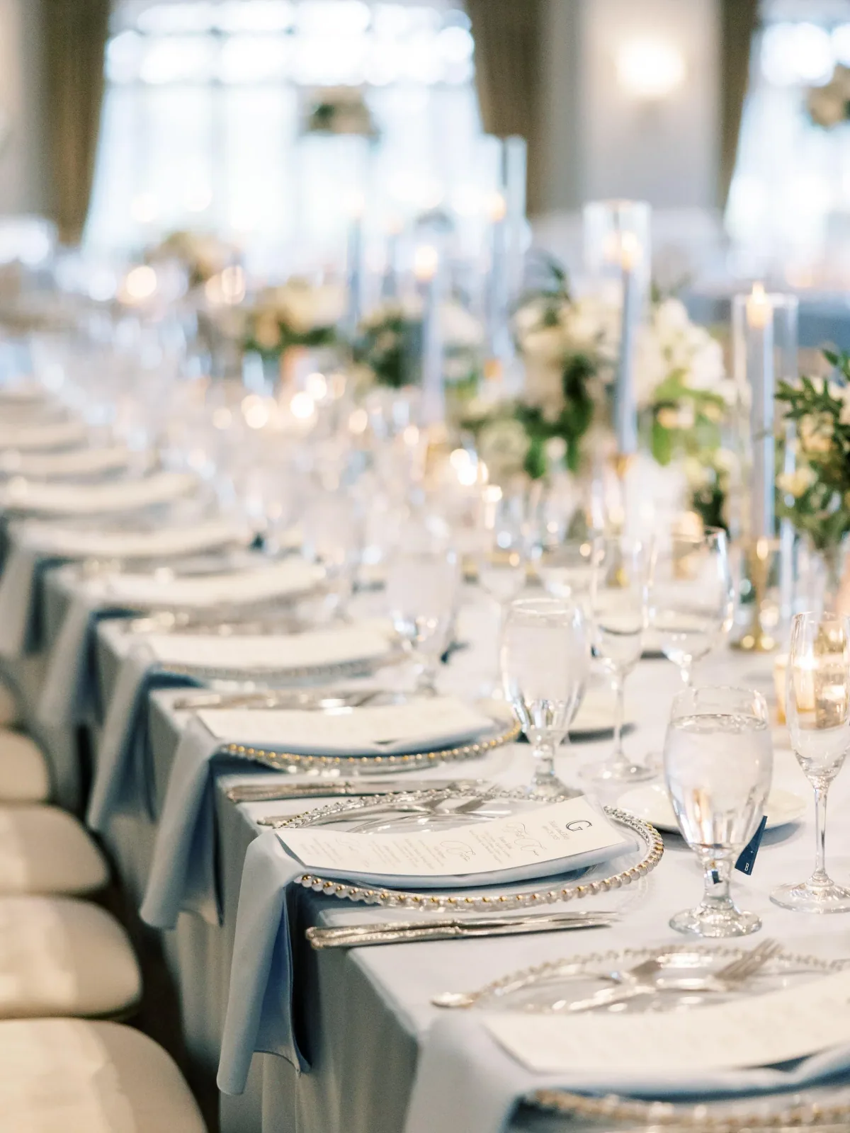Long reception tables set with dusty blue linens and printed menus