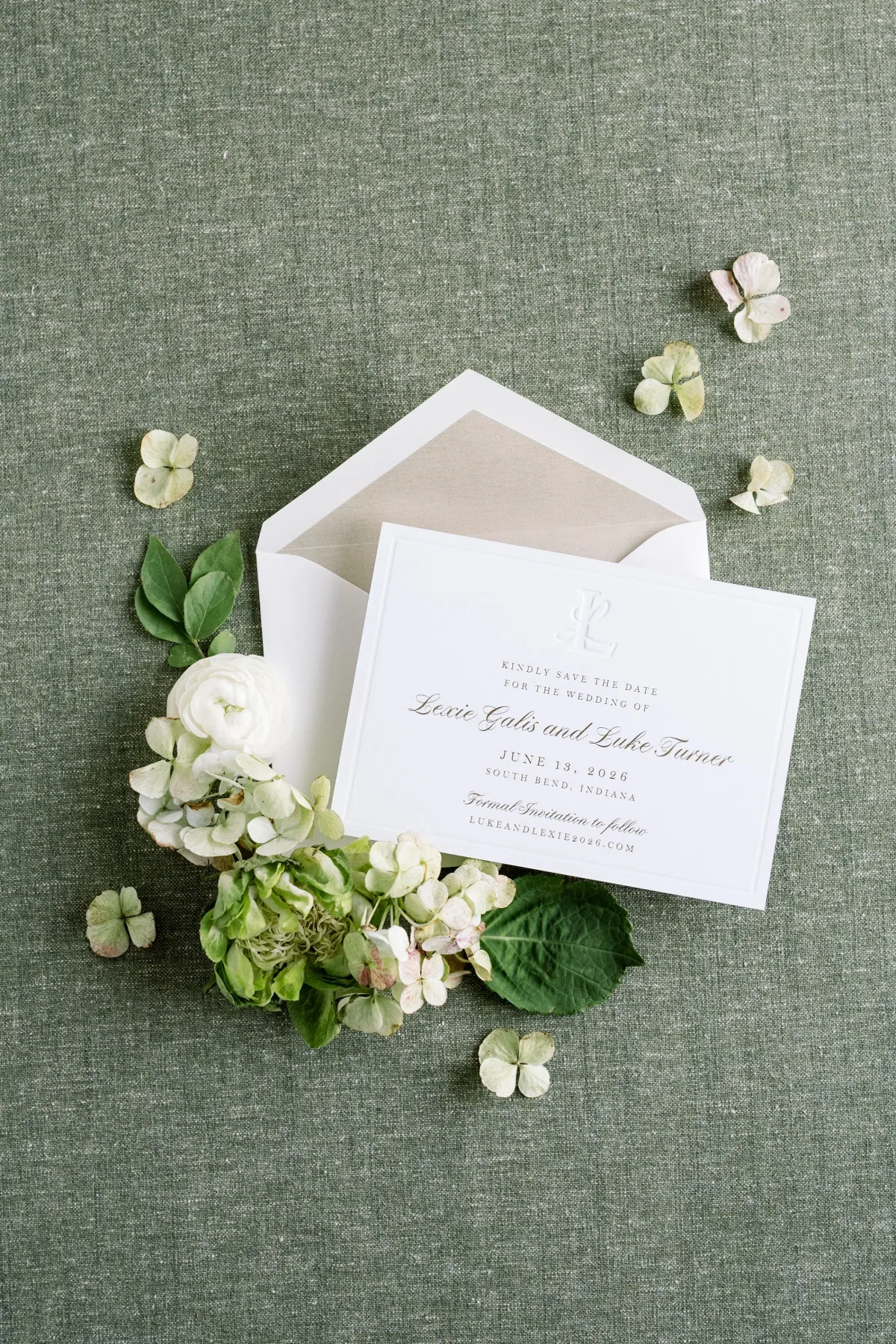Save the date card with a taupe-lined envelope on green linen