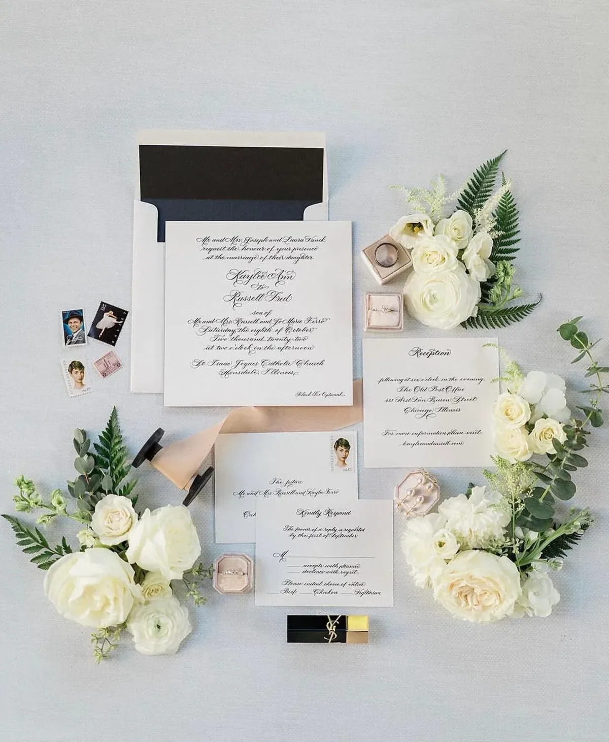 Calligraphy wedding invitation with a black-lined envelope and white florals
