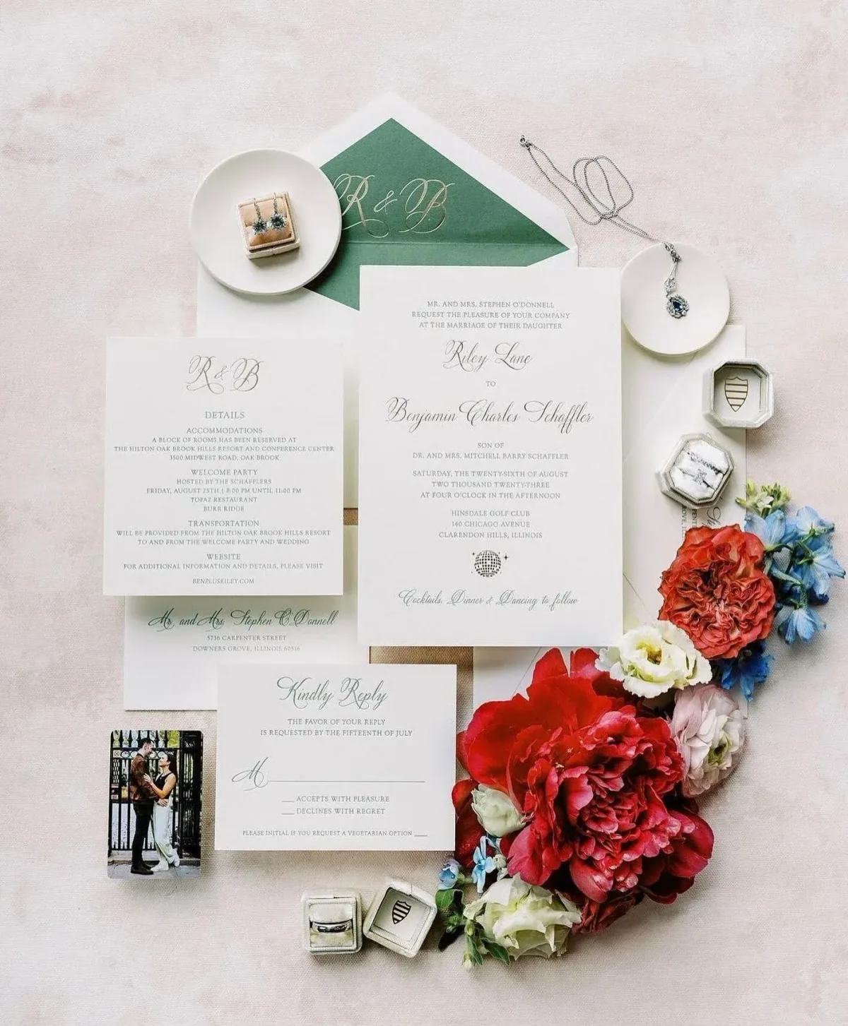 White wedding suite with a green envelope liner, styled with red blooms