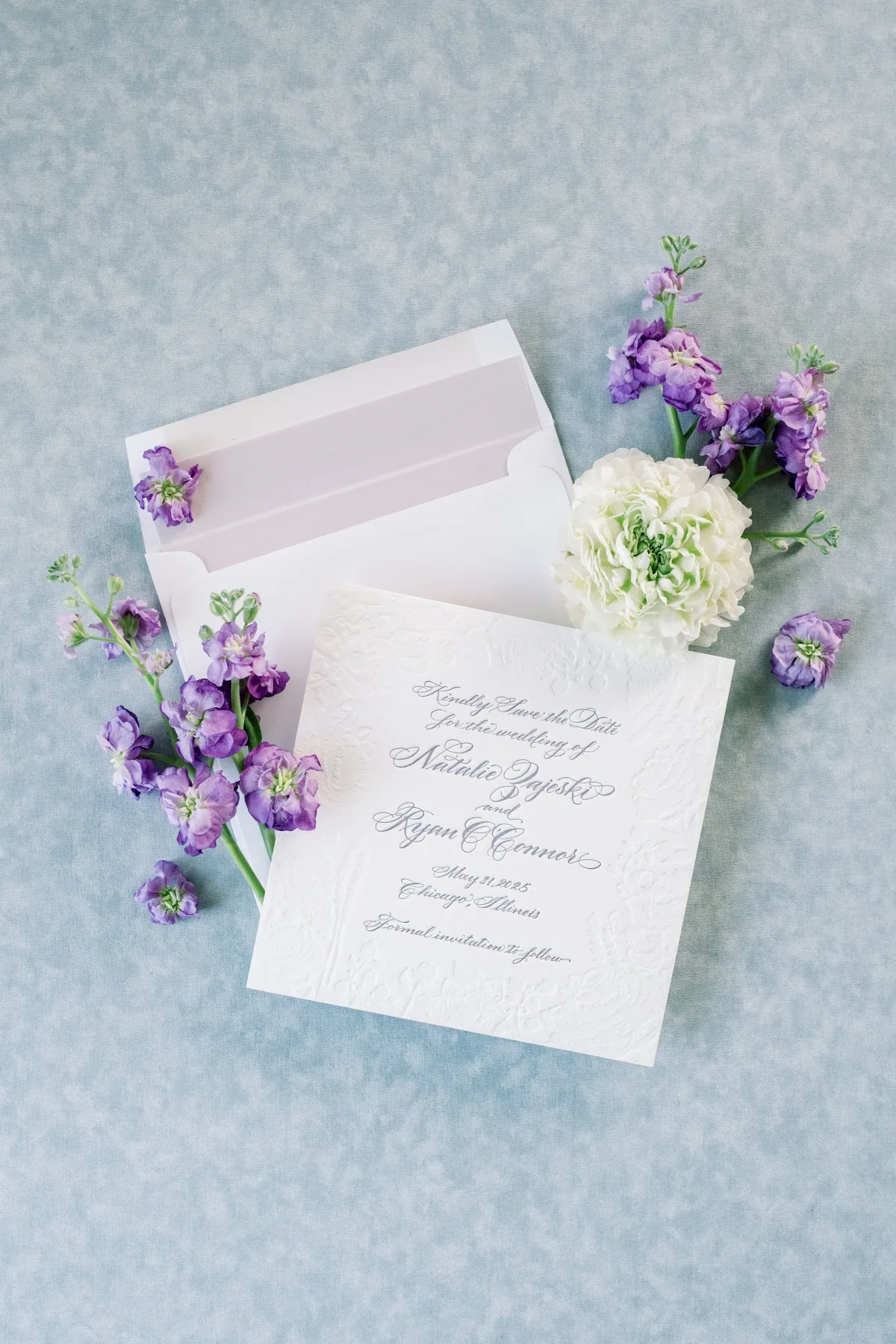 Save the date on a textured white card with a lavender-lined envelope